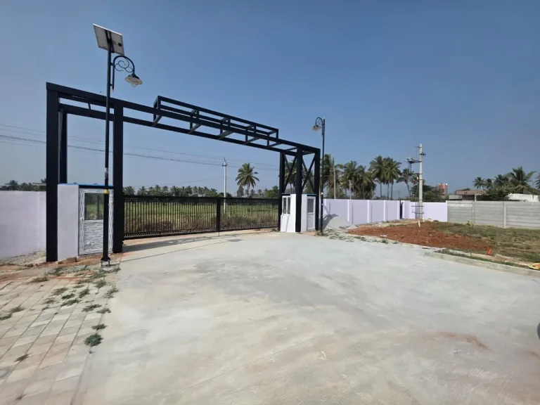 Gated residential property entrance with solar-powered street lights, landscaped grounds, and palm trees.