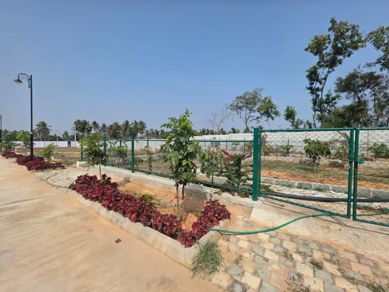 Landscaped residential property with flowering plants, green fencing, paved walkways, and decorative street lighting.